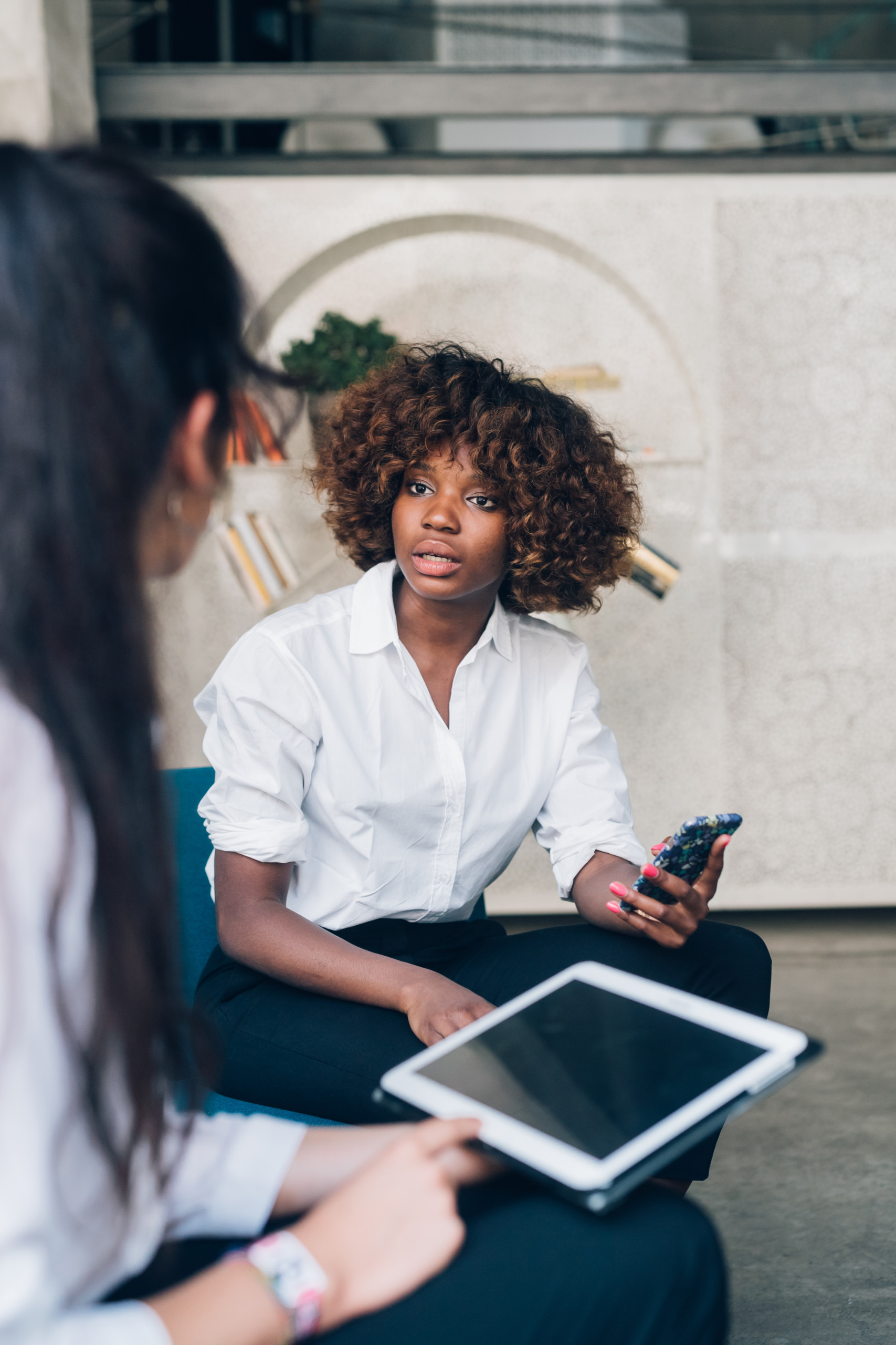 Firstbird: Zwei schwarze Frauen diskutieren in einem Büro.