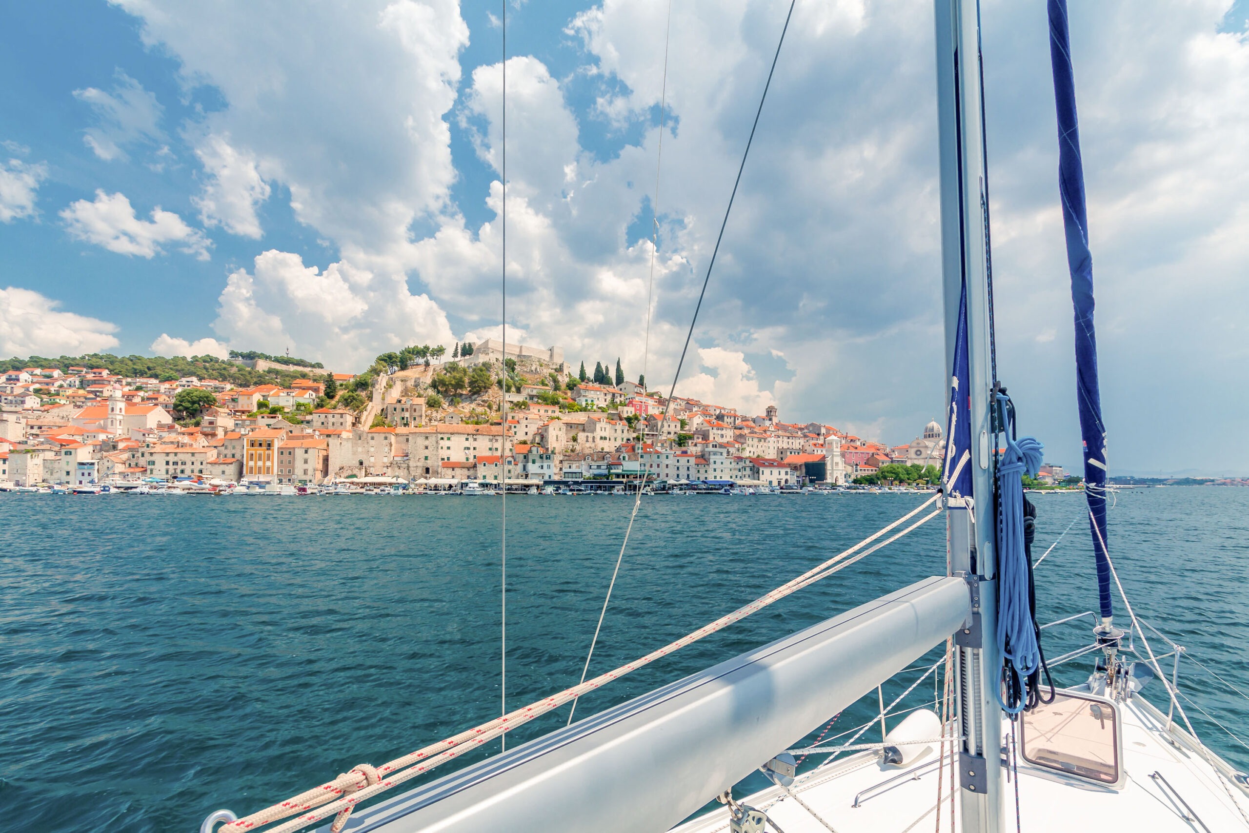 A view of a city from the deck of a sailboat.