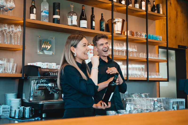 Two bartenders standing in front of a bar.