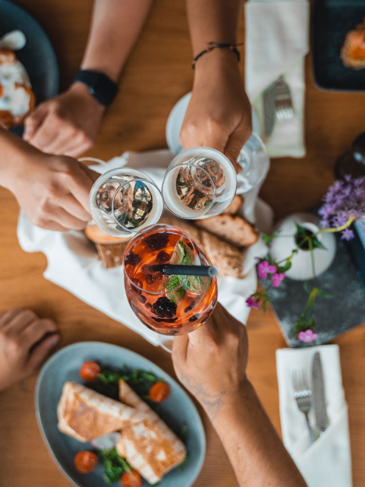 A group of people toasting at a table with food and drinks.