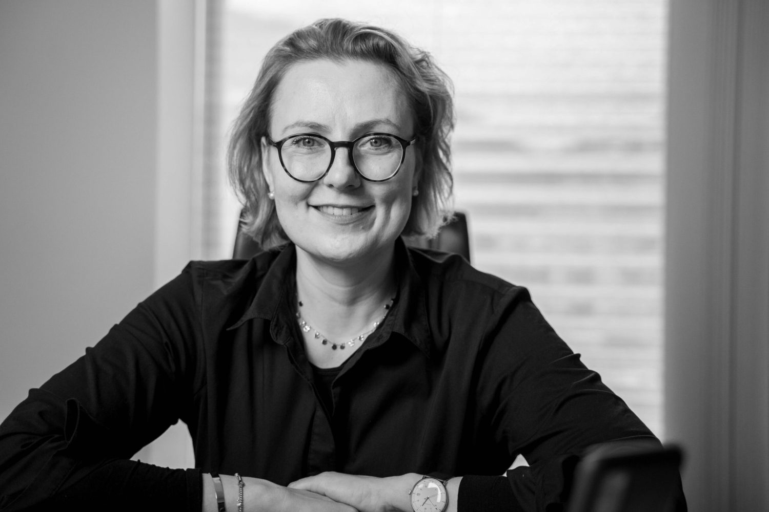 A black and white photo of a woman smiling at a desk, emphasizing PMT.