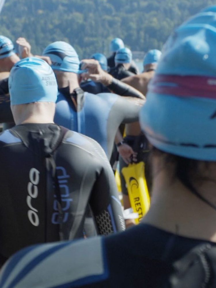 A group of swimmers in wetsuits standing on a dock at the Austria Swim Open.