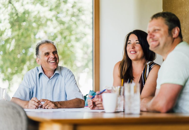 A group of people sitting around a table at a Breitling+Partner event and smiling.