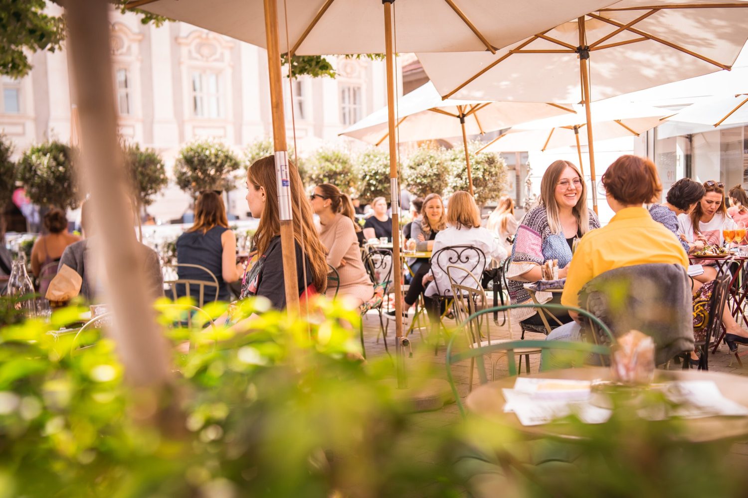 A group of people sitting at tables in an outdoor Kunsthauscafé.