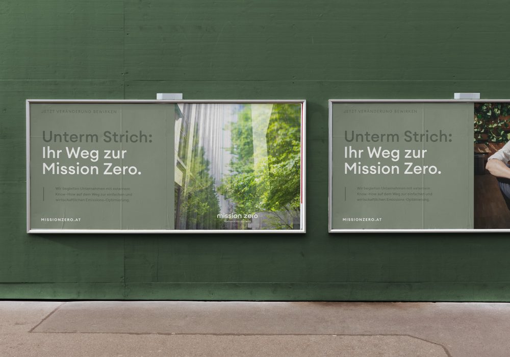 Zwei Werbetafeln, die für Mission Zero werben, an der Seite einer grünen Wand.