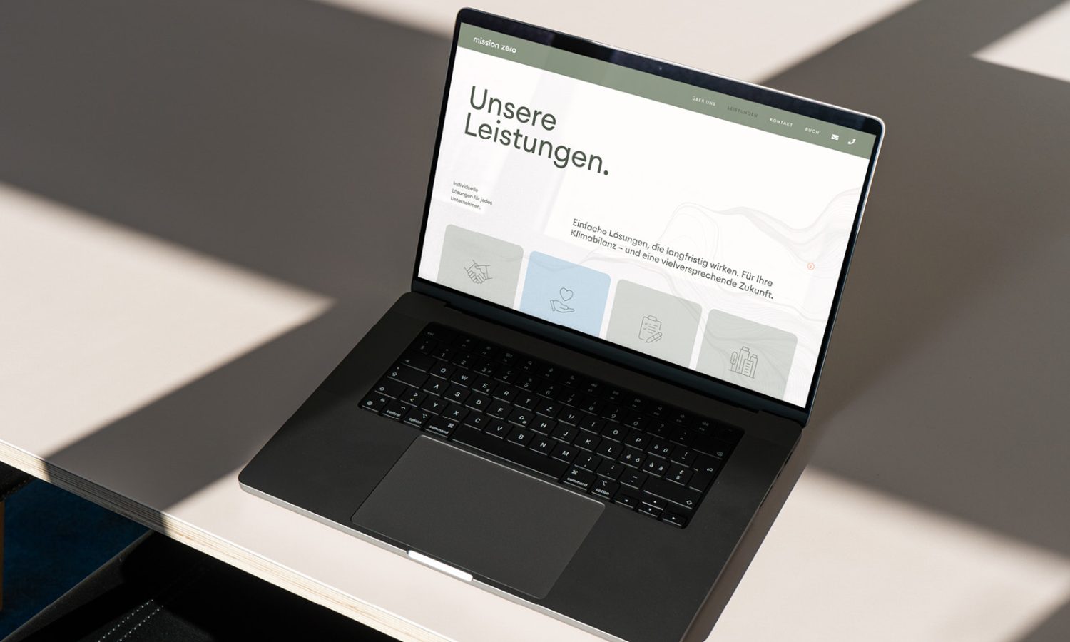 Auf einem Schreibtisch vor einem Fenster steht ein Laptop, auf dem Mission Zero zu sehen ist.
