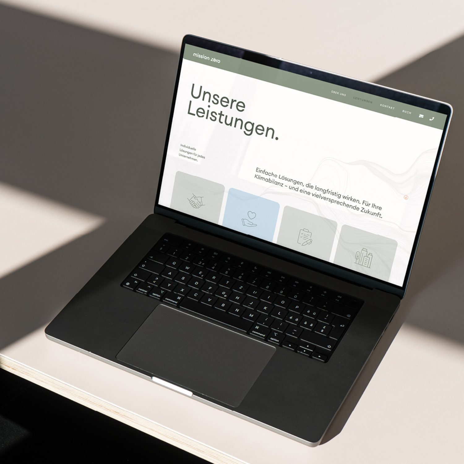 Auf einem Schreibtisch vor einem Fenster steht ein Laptop, auf dem Mission Zero zu sehen ist.