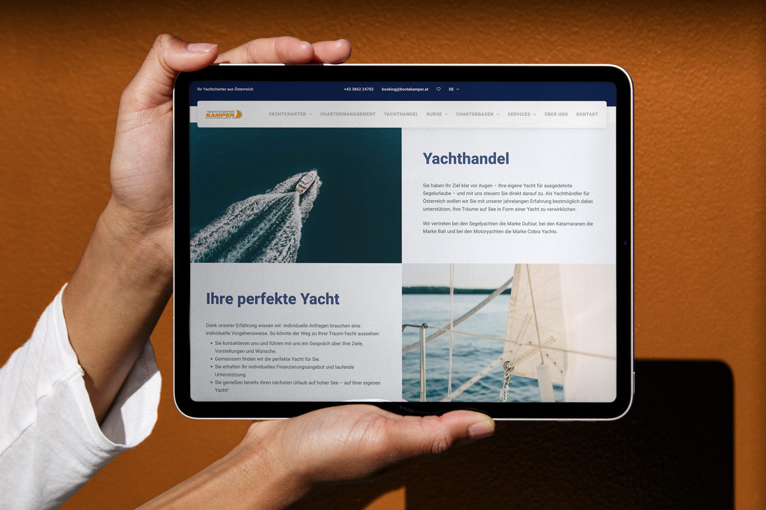 Eine Person hält ein iPad mit einem Bild einer Yacht darauf. Eine Person hält ein iPad mit einem Bild einer Yacht darauf.