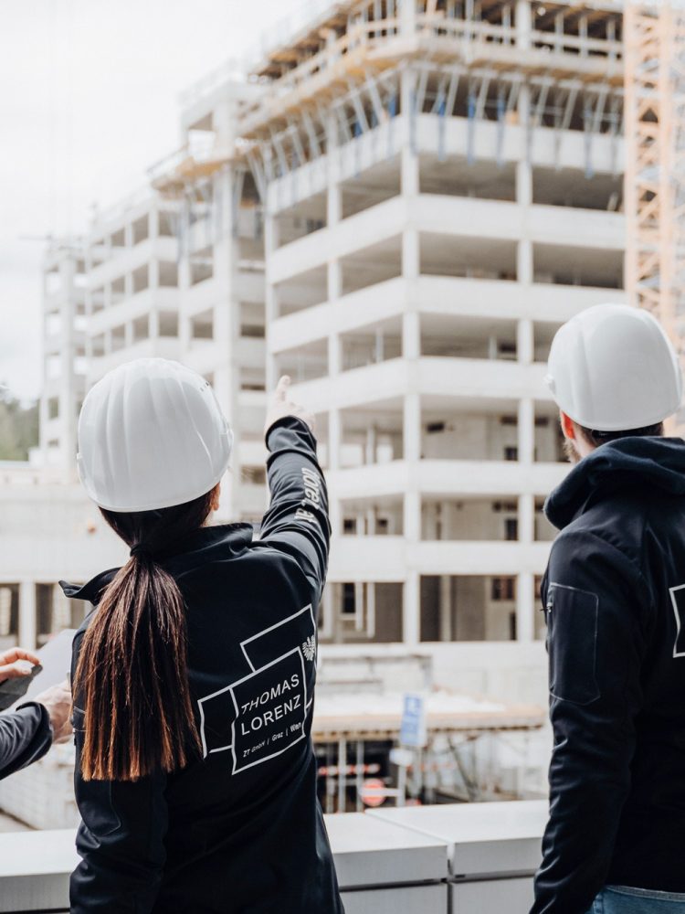 Three construction workers standing on a roof overlooking a construction site with the keyword "construction site.