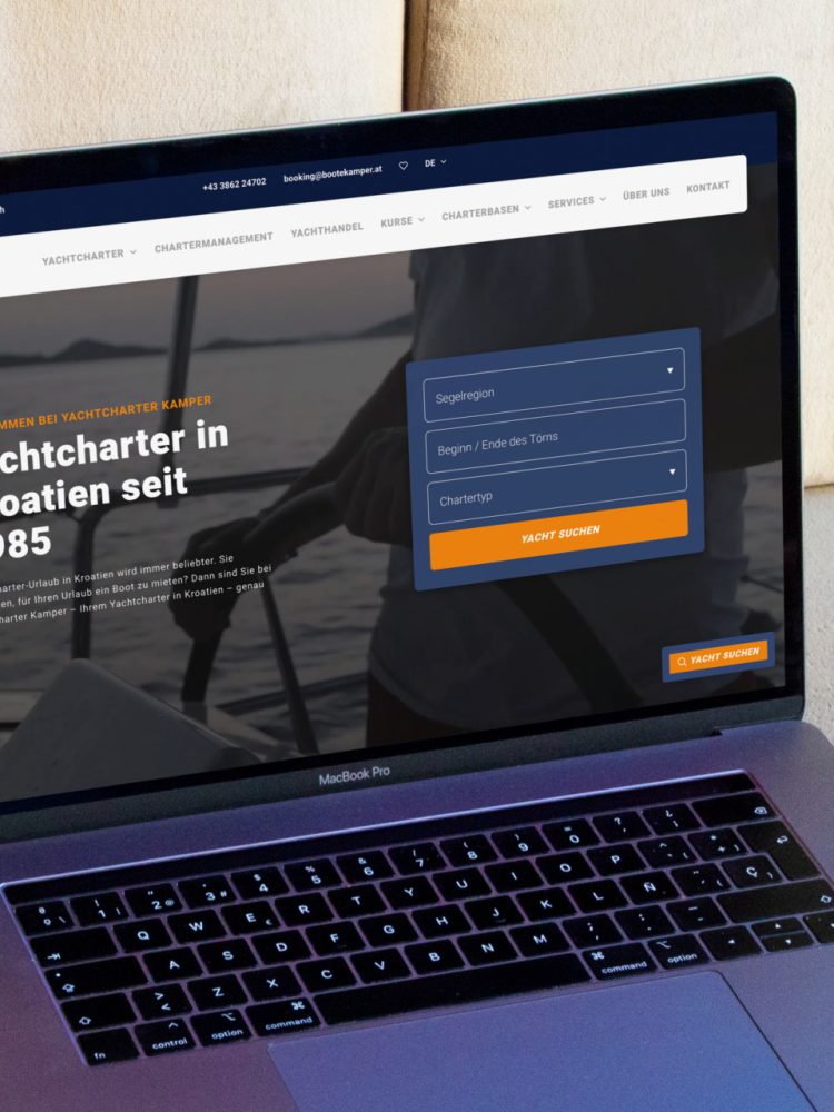 Auf einer Couch liegt ein Laptop mit einer Yachtcharter-Website.
