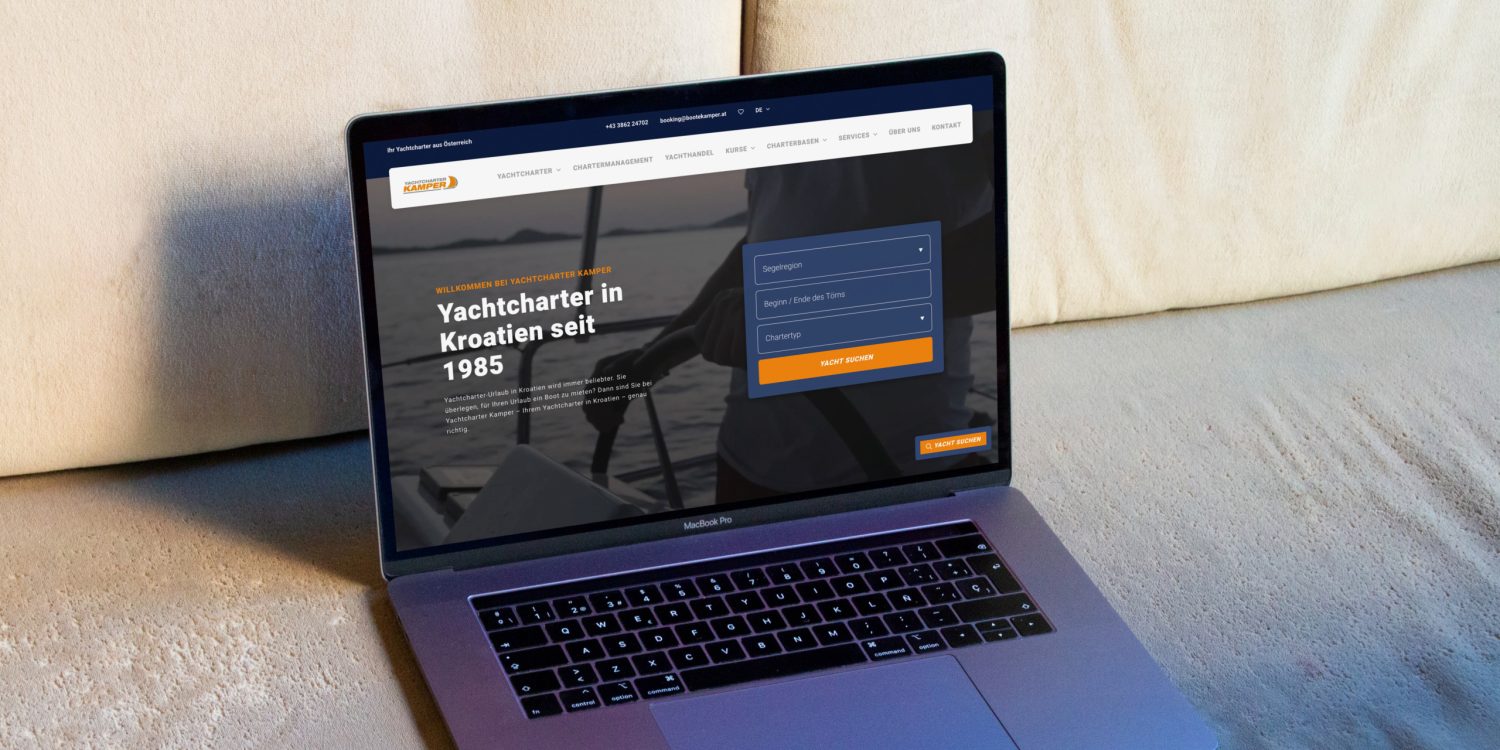 Auf einer Couch liegt ein Laptop mit einer Yachtcharter-Website.