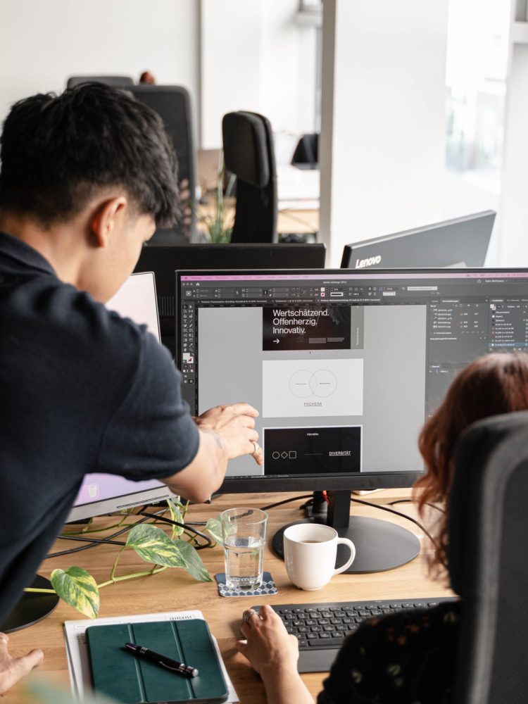 Two people working at a desk in an office.