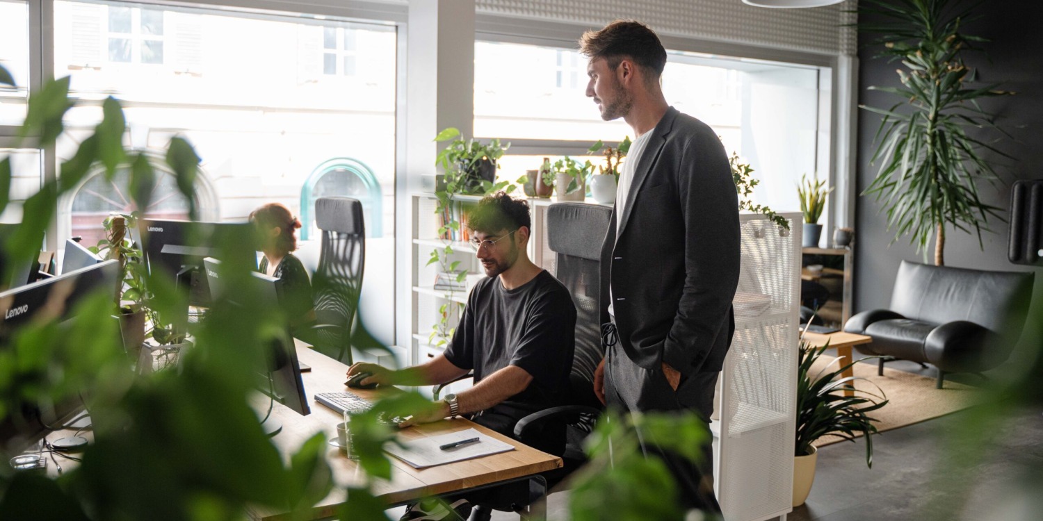 A group of people working in an office with plants.