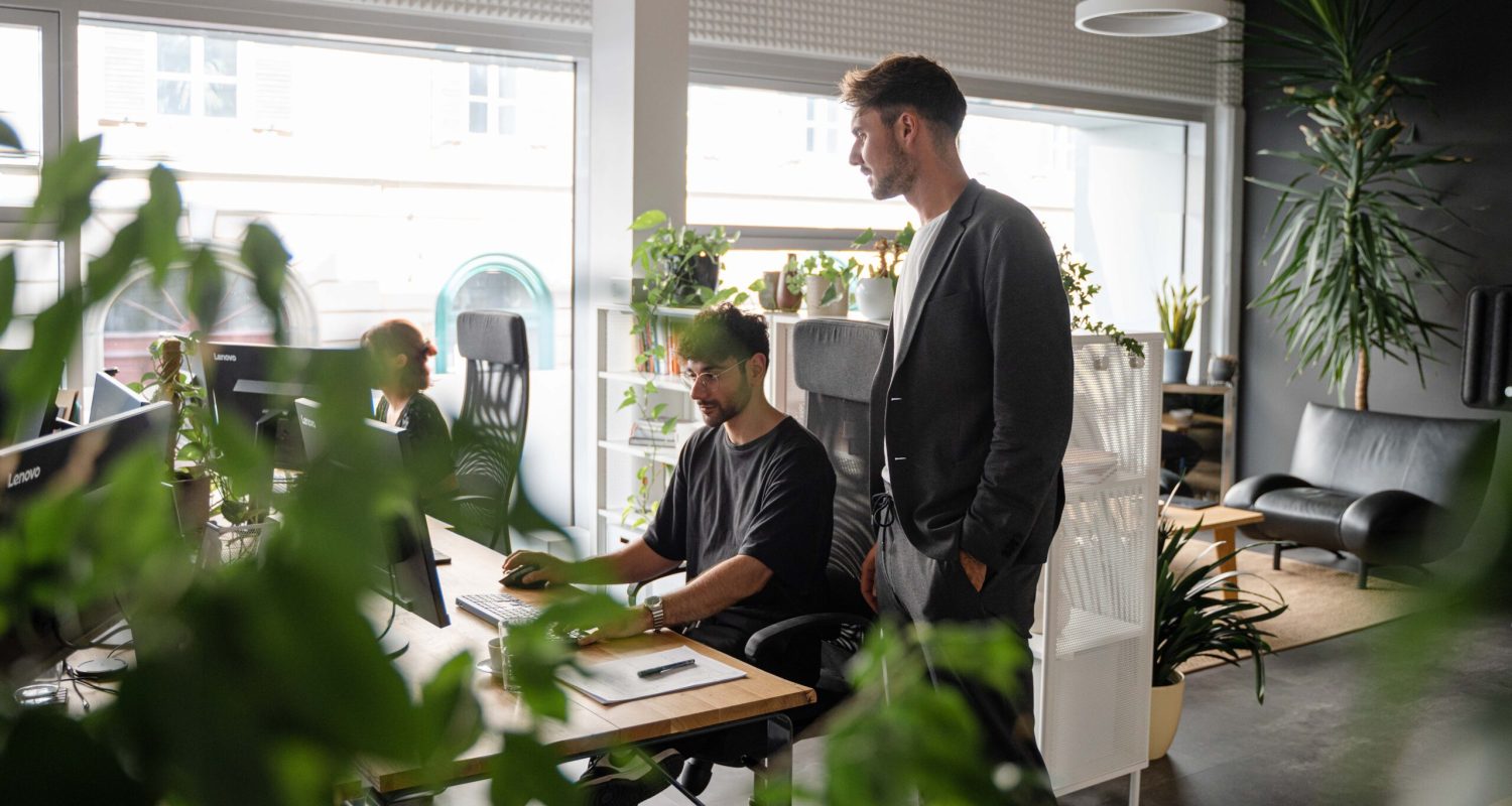 A group of people working in an office with plants.