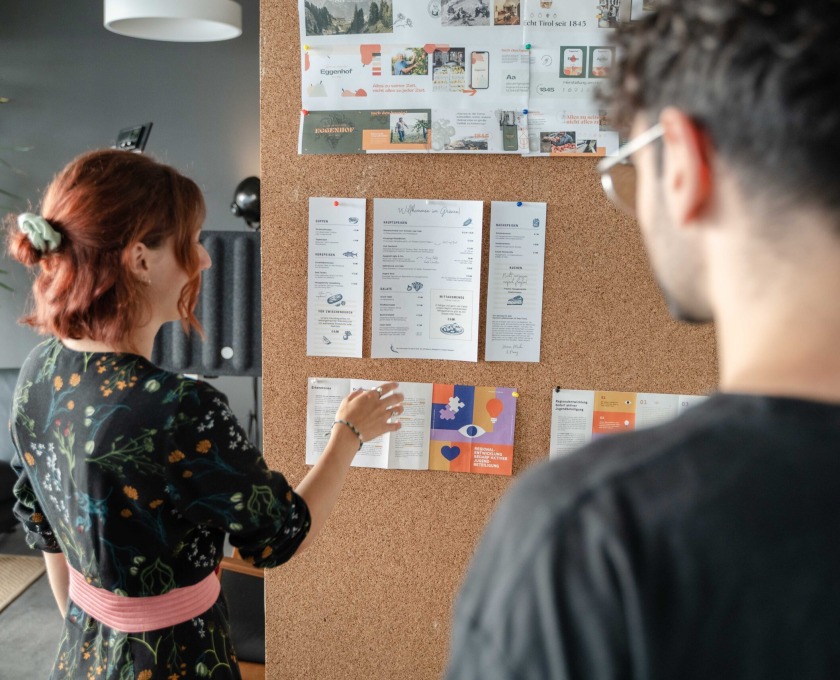 A woman and a man looking at a bulletin board.