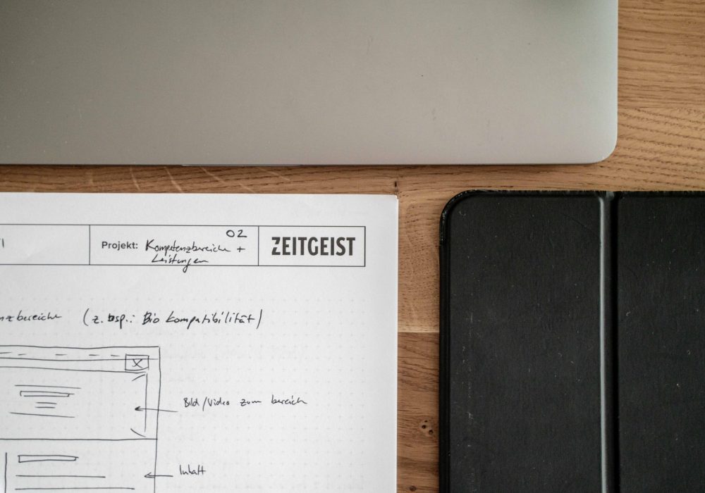 A notebook on a table next to a laptop and a tablet.