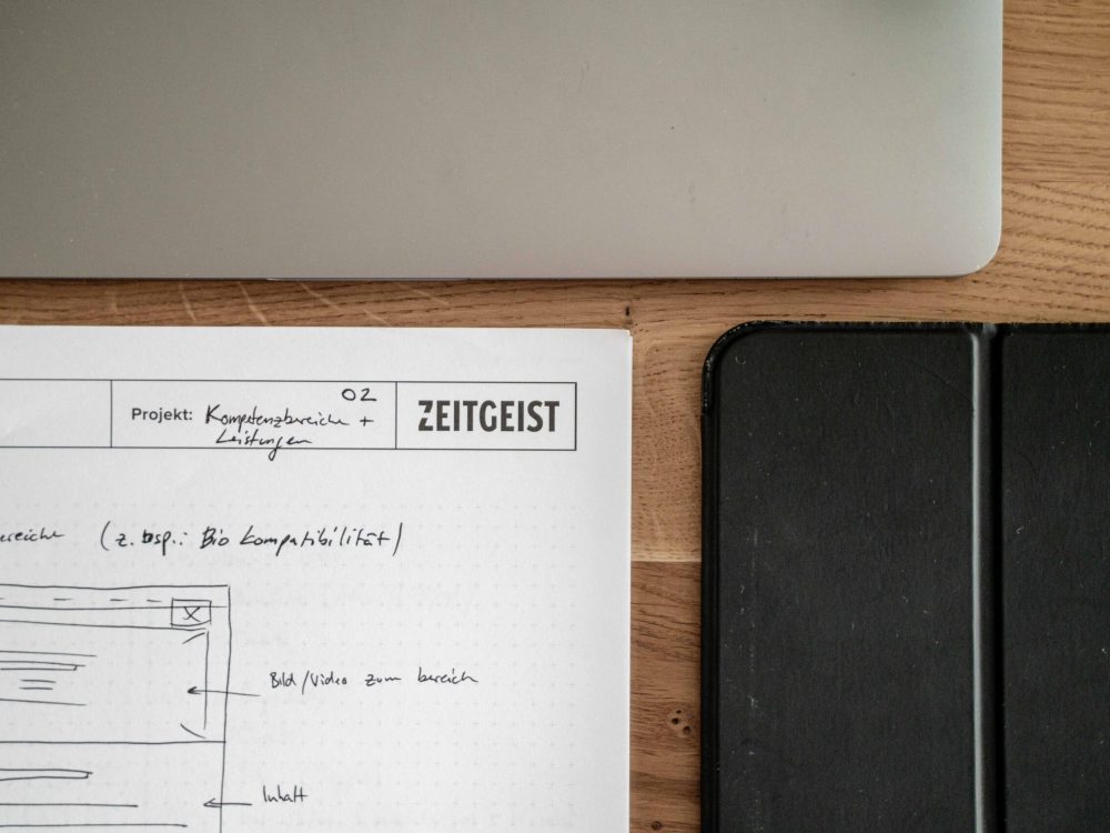 A notebook on a table next to a laptop and a tablet.