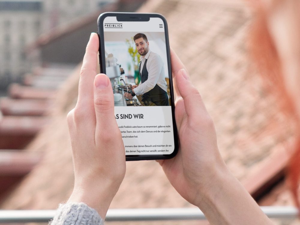 Eine Frau macht mit ihrem Handy ein Foto vom Restaurant Freiblick.