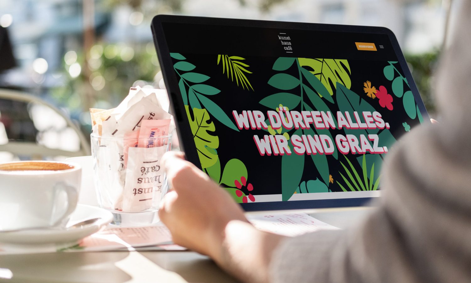 Eine Person sitzt mit einem Laptop und einer Tasse Kaffee an einem Tisch im Kunsthauscafé. Eine Person sitzt mit einem Laptop und einer Tasse Kaffee an einem Tisch im Kunsthauscafé.